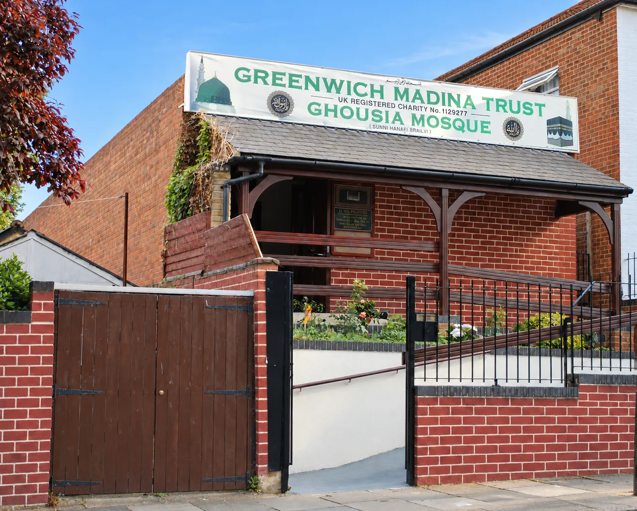 Ghousia Masjid on Camrose Street on a clear day: the timber porch beneath the Greenwich Madina Trust sign